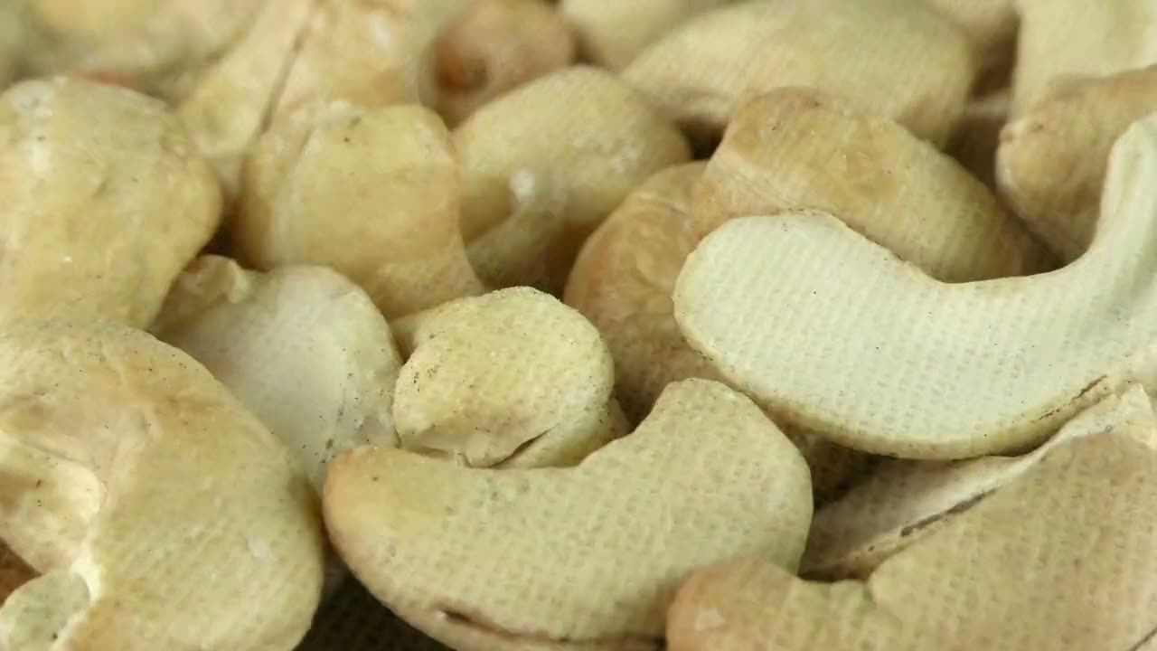 An almond orchard in the sun, then almonds and cashew nuts falling onto jute cloth, cashew nuts in extreme close-up and a mix of dried fruit.